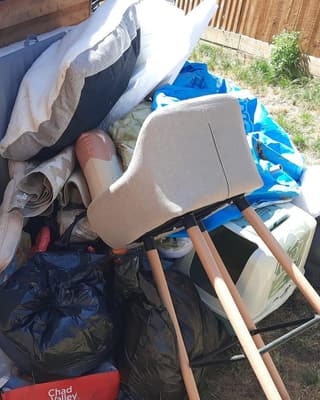 Before: a mattress, a chair and bin bags piled against a shed